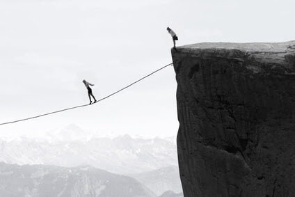 Image of businesswoman taking risk and walking on the rope over the gap